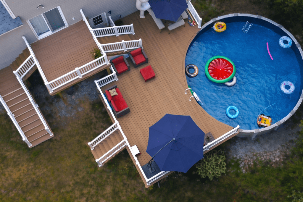 Aerial view of a custom composite deck with white railings and an above-ground pool at a New Hampshire home.